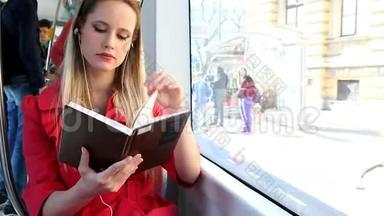 美丽的金发女人坐在电车上，看书，接电话